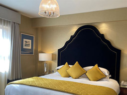 A king bed with a tall head board and yellow decor in a room at Brooks Hotel in Dublin
