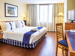 A double bed in a room with a desk and TV at Holiday Inn Lisbon 