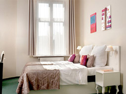 Two beds in a room with a large window and beside table at ApartHotel Leone in Krakow