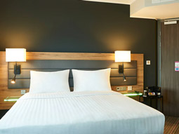 A double bed in a room with warm bedside lighting at Moxy Southampton