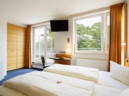 Two beds in a room with large open windows and a balcony at MesseHotel Köln-Deutz