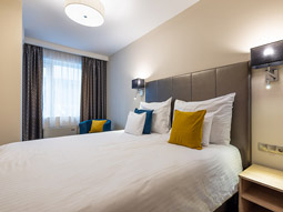 A double bed with decorative cushions on at Silver Crown Hotel and Residence