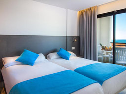 Two single beds beside a large window that opens onto a balcony at La Era Park Apartments