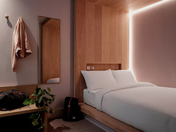 A double bed in the corner of a room with a mirror beside it 