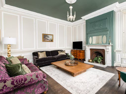 The lounge at Harcombe House which is spacious, ornate and features two sofas and a fireplace 