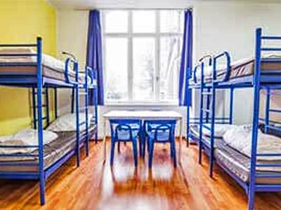 Blue bunkbeds along the sides of a room with a table and chairs in the middle