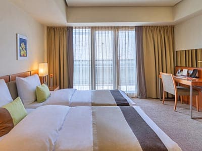 Two beds in a hotel room, facing a desk and desk chair against the opposite wall