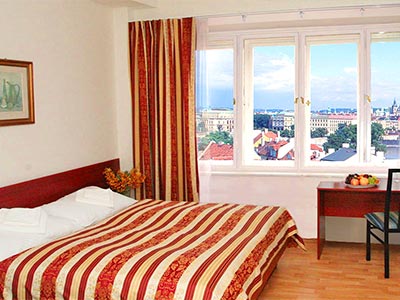A bed in a hotel, with red and white striped bedding, with a chair facing the windows in the back - Rank #5