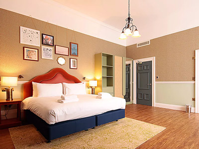 A double bed in a room with artwork above the bed and storage areas at Elmbank Hotel and Lodge