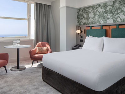 A double bed in a room with a small area to sit at with a big window at Doubletree by Hilton
