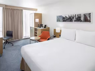A double bed in a room with a desk area, large windows and lots of storage at DoubleTree By Hilton Manchester Piccadilly