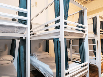 Multiple bunk beds with their own blue curtains to go around them at Safestay Barcelona Gothic