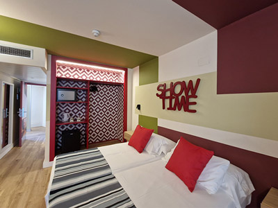 A twin room with a red, green and grey theme at Hotel Marina in Benidorm