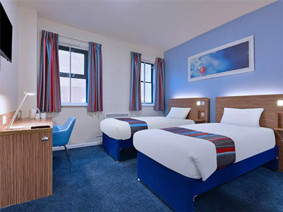 Two single beds in a room with art above the bed at Travelodge Leeds Central Vicar Lane
