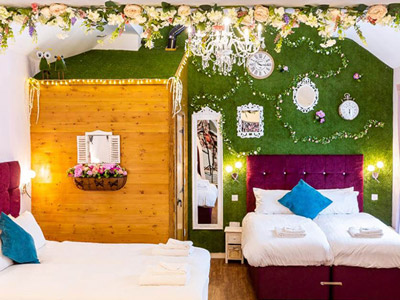 A close up of a bed against a green wall with fairy lights and floral decor at Through the Looking Glass in Newcastle