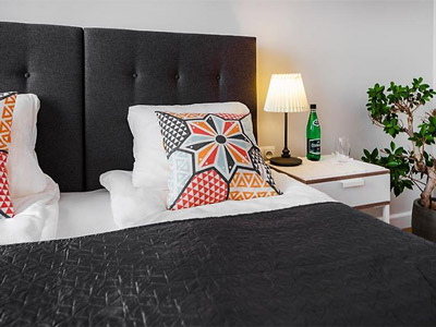 A close up of a patterned cushion on a bed with a bedside light beside it at Six Suites in Gdansk