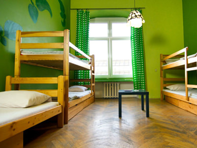 A hostel room with several bunk beds and green decoration