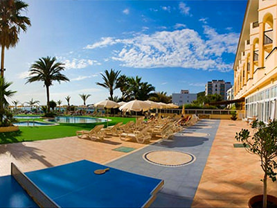 A view of a hotel pool with sun beds and several palm trees