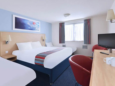 A room with a double bed and single bed with a desk and chair in front of it at Travelodge Birmingham Central