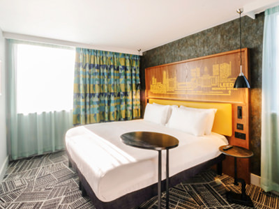 A hotel room with a double bed and table