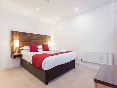 A double bed with red blankets and cushions at Premier Suites Bristol Cabots Circus