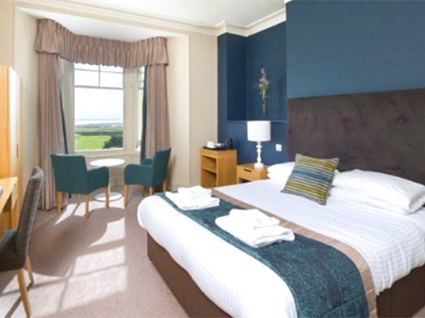 A double room with lots of storage, desk space and a set of chairs that look out onto the countryside at Trecan Hotel in Torquay