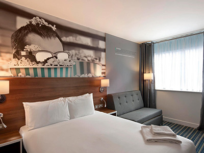 Bedroom with white double bed and sofa at Heeton Concept Hotel Liverpool 