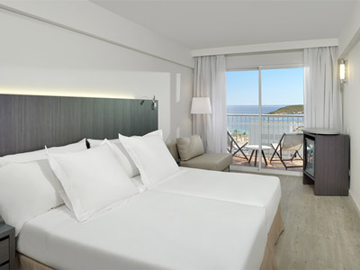 A king room with a balcony that overlooks the sea and city with deck chairs at Sol House in Magaluf