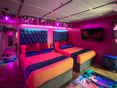 A room with two double beds in and pink neon lighting at Copper and Blossom Suite