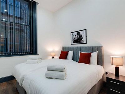 A twin room with big windows and bedside tables at Harrisons Apartments in Liverpool