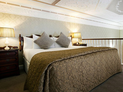 A king bed with bedside tables beside it at The Harrington Hall Hotel in Dublin