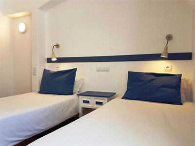A twin room with lighting above each bed and a bedside table at Soldoiro Apartments in Algarve