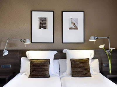 A close up of a double bed in a brown/natural themed room with artwork above the bed at Hotel Medium in Valencia 