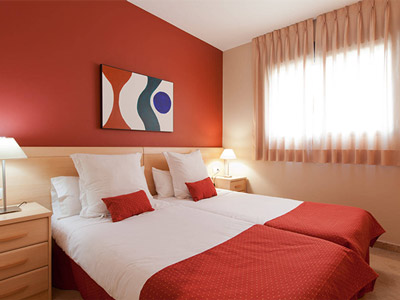 A red coloured wall with abstract artwork above a double bed at Apartamentos Plaza Picasso in Valencia