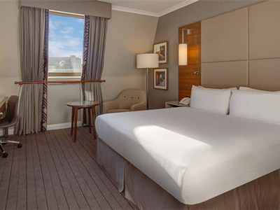 A king bed with a window that overlooks the city at Hilton Cambridge City Centre