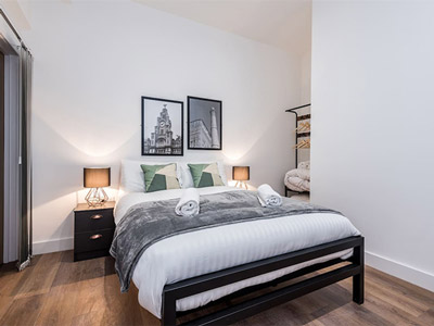 A double bed with a blanket over it and artwork above the bed at Sgt Peppers Liverpool