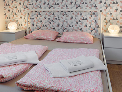 A double bed in a room with geometric wallpaper on and two lamps at Patio Hostel in Bratislava