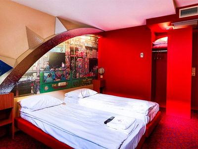 Two twin beds in a red themes room with a patterned wall behind them at The Bull Dog Hotel in Amsterdam