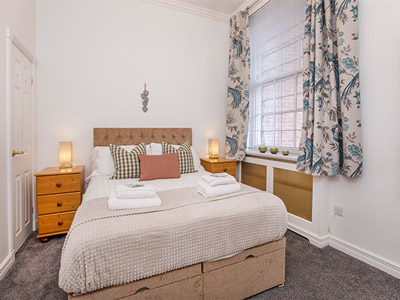 A double bed in a room with warm lighting at Shambles York Apartments
