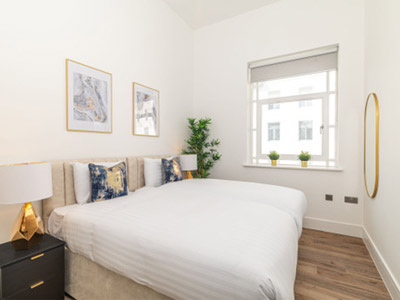 A king bed in a room with framed art on the wall and a mirror at Fenwick Street Apartments in Liverpool