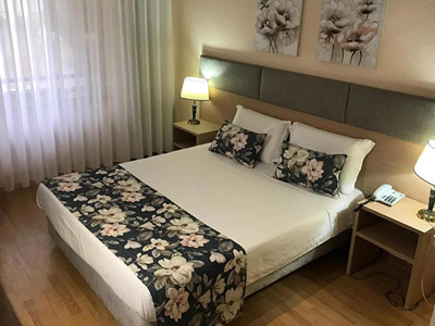 A double bed in a room with patterned artwork and bed decorations at Hotel Excelsior