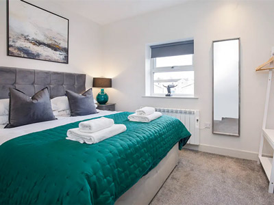 A double bed with a green quilted sheet at Bishopthorpe Apartments in York - Rank #4