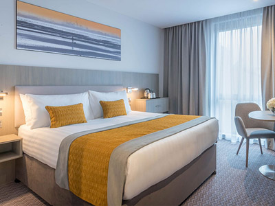 A room with a double bed and artwork above it at Maldron Hotel in Glasgow