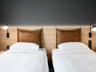 Two single beds against leather headboards at Moxy Bristol