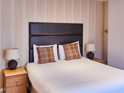 A room with a double bed and bedside tables in an apartment at Queens Hotel in Brighton