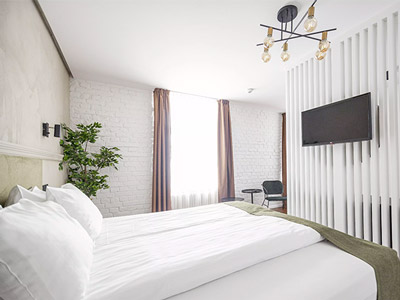 A bed facing a TV with a large window beside it at Rixwell Konventa Seta Design Hotel - Rank #9