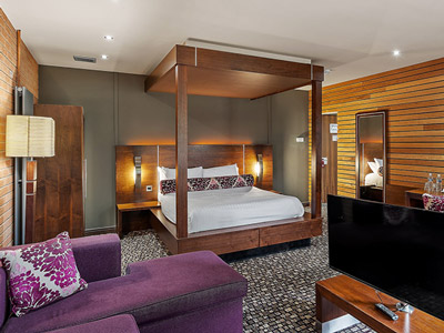 A room with a double bed, a TV and chairs at The Rutland Hotel in Sheffield 