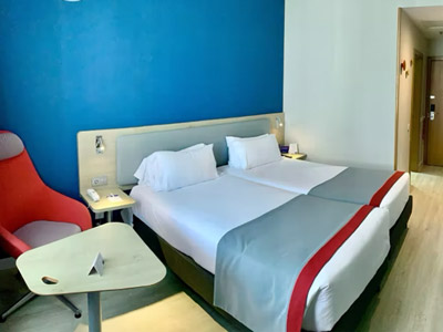 A double bed in a room with a bright blue wall and bedside tables at Holiday Inn Express Valencia-Ciudad las Ciencias
