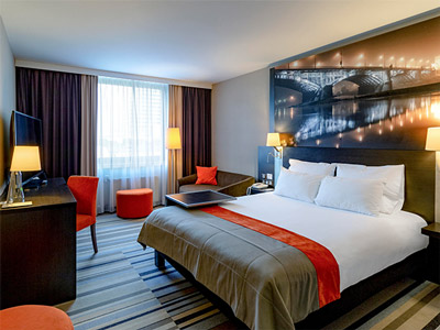 A double bed with a desk area and seats at Hotel Mercure Warszawa Centrum
