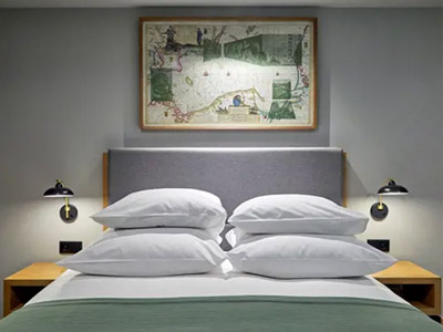 A double bed with puffed up pillows and artwork above it at Puro Gdansk